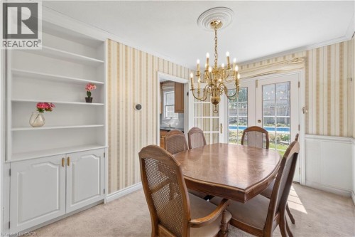 Dining area featuring French doors, a brass chandelier, built-in shelving with lower cabinetry, and wainscoting - 277 Blackacres Boulevard, London, ON 