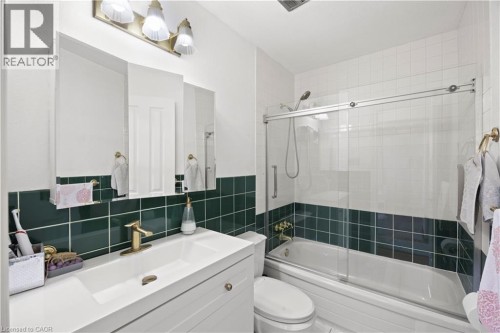 Bathroom featuring a white vanity with integrated sink, brass-finish faucet, and a tri-fold mirrored medicine cabinet - 277 Blackacres Boulevard, London, ON 