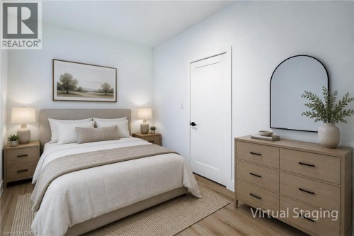 Bright bedroom featuring light-toned wood-finish flooring, a contemporary white door with black hardware, and crisp white walls - 78 Hillyard Street, Hamilton, ON 
