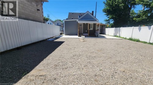 Gravel-surfaced yard featuring a new concrete patio and a multi-sided privacy fence - 78 Hillyard Street, Hamilton, ON 