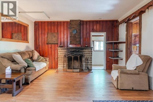 Spacious room featuring wood-finish flooring, a prominent stone fireplace, and rustic wood-paneled accent walls - 382 Beach Boulevard, Hamilton, ON 