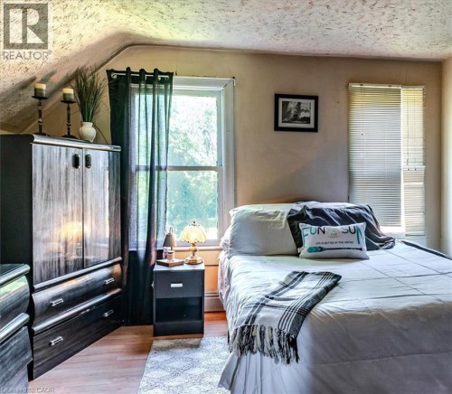 Room featuring wood-finish flooring, a double-hung window, and a second window with horizontal blinds - 382 Beach Boulevard, Hamilton, ON 