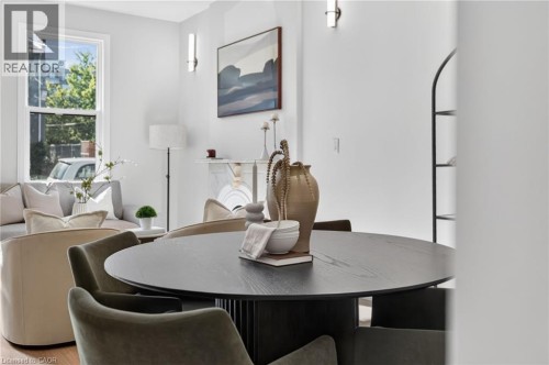 Open-concept living area featuring a prominent circular wood-finish dining table, recessed lighting, and wall-mounted sconce fixtures - 118 Cathcart Street, Hamilton, ON 