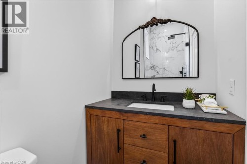 Hardwood vanity with dark stone countertop, integrated rectangular sink, and matte black faucet - 118 Cathcart Street, Hamilton, ON 
