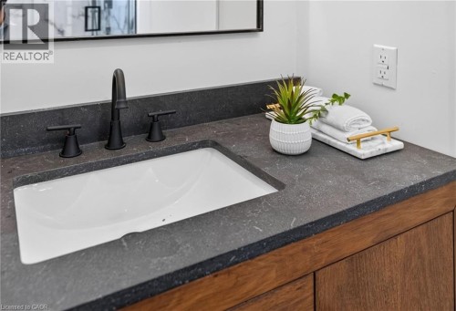 Built-in vanity featuring a dark countertop with an integrated white sink and matte black faucet - 118 Cathcart Street, Hamilton, ON 