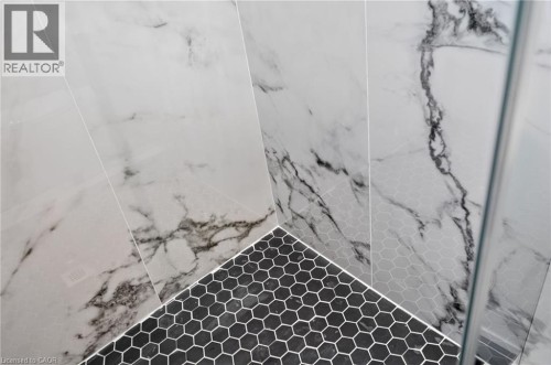 Shower enclosure with white marble-patterned wall tiles and black hexagon mosaic floor tiles - 118 Cathcart Street, Hamilton, ON 