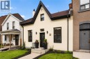 Cream stucco exterior with black trim, a prominent front gable, and a black front door featuring decorative glass - 118 Cathcart Street, Hamilton, ON 