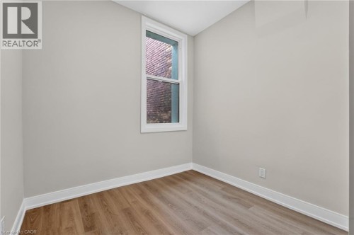 Bright room with wood-finish flooring, light-colored walls, white trim, and a white-framed window - 118 Cathcart Street, Hamilton, ON 