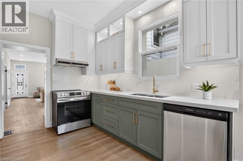 Contemporary kitchen featuring two-tone cabinetry, stainless steel appliances, and a double basin sink with a gold-tone faucet - 118 Cathcart Street, Hamilton, ON 