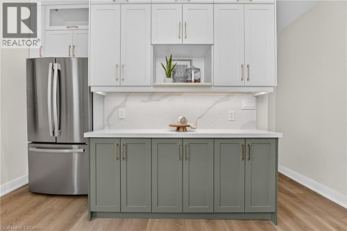 Contemporary kitchen area featuring two-tone cabinetry with white upper cabinets and sage lower cabinets, a white countertop, and a matching full-height backsplash - 118 Cathcart Street, Hamilton, ON 