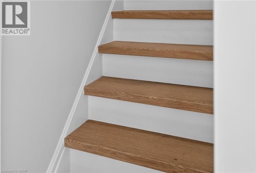 Staircase featuring wood-finish treads and white risers - 118 Cathcart Street, Hamilton, ON 