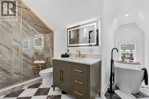 Contemporary bathroom featuring a freestanding tub, glass-enclosed shower with large format tile, and a single vanity with a stone countertop - 118 Cathcart Street, Hamilton, ON 