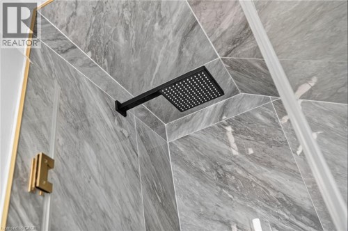 Rainfall showerhead with a matte black finish, set against gray marble-look tile walls with white grout lines - 118 Cathcart Street, Hamilton, ON 