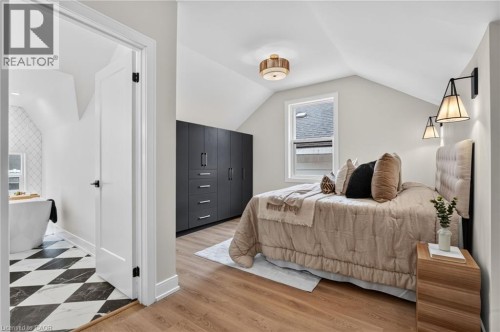 Bedroom featuring wood-finish flooring, a built-in dark cabinetry system with drawers, and a window - 118 Cathcart Street, Hamilton, ON 