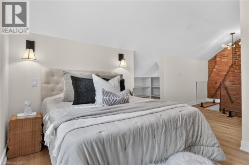 Bedroom featuring an upholstered headboard, wood-finish flooring, and sloped ceilings - 118 Cathcart Street, Hamilton, ON 