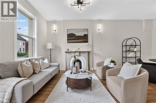 Living space featuring light wood-finish flooring and a decorative fireplace with a detailed mantel - 118 Cathcart Street, Hamilton, ON 