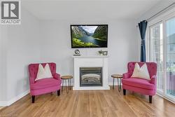 Living area featuring light wood-finish flooring, a white mantelpiece, a built-in fireplace, and a sliding glass door - 