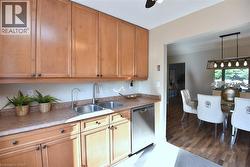 Kitchenette featuring wood cabinetry, a double basin stainless steel sink with a gooseneck faucet, a stainless steel dishwasher, and a laminate countertop - 