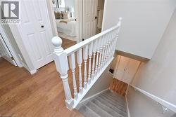 Staircase featuring white balusters and handrail, carpeted treads, and neutral wall paint - 