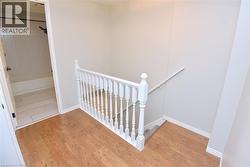 Light wood-finish flooring with white baseboards and baluster railing leading down to a lower level - 