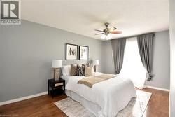 Bedroom featuring wood-finish flooring, a ceiling fan with integrated lighting, and a window with drapery - 