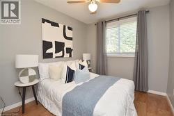 Bedroom featuring wood-finish flooring, a window with blinds, a ceiling fan with integrated lighting, and neutral wall tones - 