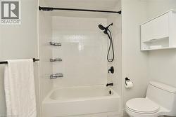 Bathroom featuring a white subway tile surround, white bathtub, and matte black shower fixtures - 