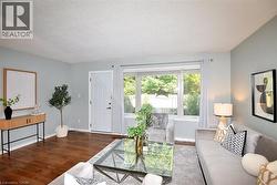 Living room featuring wood-finish flooring, a large picture window, and a paneled entry door - 