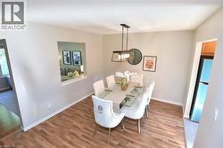 Dining area featuring wood-finish flooring, a contemporary chandelier, and a pass-through window opening - 