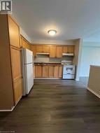Kitchen featuring wood-finish flooring, ample cabinetry, white appliance suite, and a laminate countertop - 