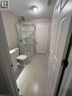 Bathroom featuring a corner shower enclosure with clear glass, a white toilet, and a white vanity with a cabinet - 