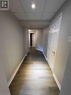 Hallway featuring wood-finish flooring, light gray walls, and white trim - 