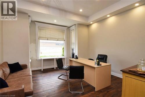 Recessed lighting illuminates the room featuring wood-finish flooring, a large window with blinds, and white window trim - 242 James Street S, Hamilton, ON 