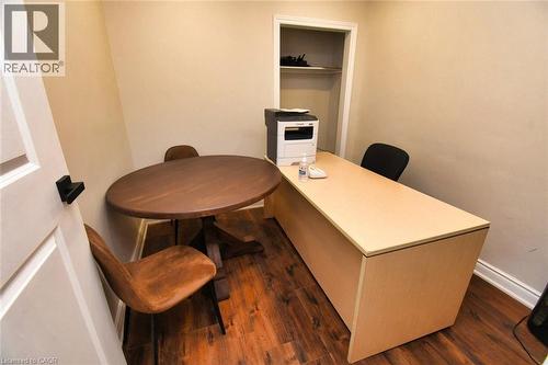Compact interior room featuring wood-finish flooring, light neutral wall paint, and white baseboards - 242 James Street S, Hamilton, ON 