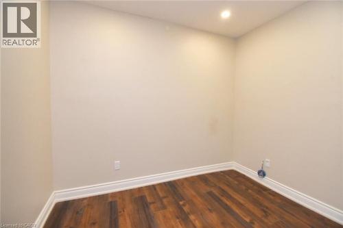 Recessed ceiling light illuminating a room with wood-finish flooring and white baseboards - 242 James Street S, Hamilton, ON 