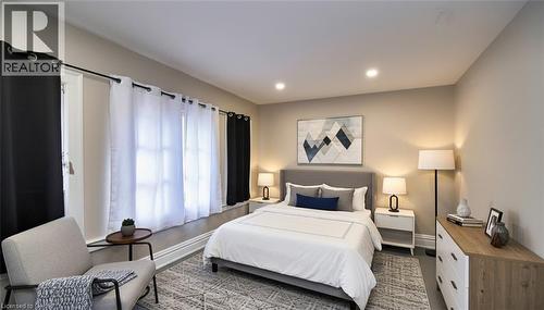 Spacious room featuring recessed lighting, a wide window with sills, neutral wall tones, and wood-finish flooring with an area rug - 242 James Street S, Hamilton, ON 