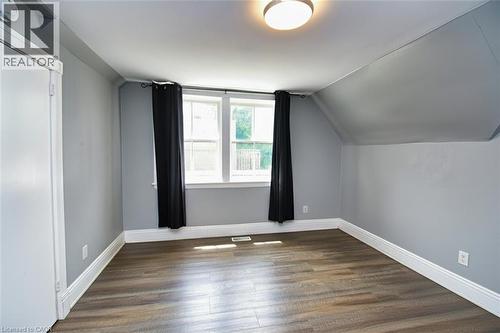 Interior room featuring wood-finish flooring, light grey painted walls, white trim, and a contemporary flush-mount ceiling light fixture - 242 James Street S, Hamilton, ON 