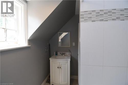 Compact bathroom featuring a white vanity with a basin sink and a framed mirror - 242 James Street S, Hamilton, ON 