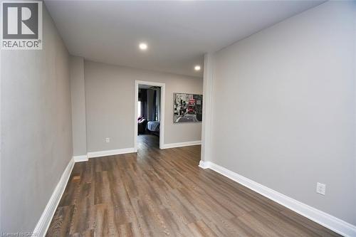 Interior corridor featuring wood-finish flooring, light gray wall paint, recessed lighting, and white baseboards - 242 James Street S, Hamilton, ON 