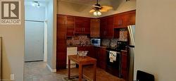 Kitchen featuring wood-finish cabinetry, patterned tile backsplash, and dark countertops - 
