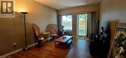 Living area featuring wood-finish flooring, a sliding glass door, and a large window - 