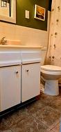 Bathroom featuring a toilet and vanity with white cabinetry, a light-toned countertop, and a basin - 