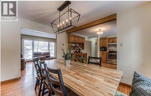 Dining area featuring wood-finish flooring, a contemporary linear chandelier, and a wood beam accent - 110 Wren Place Unit# Upper, Kitchener, ON - Indoor Photo Showing Dining Room