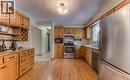 Full kitchen featuring wood cabinetry, stainless steel appliances, wood-finish flooring, a tile backsplash, and a built-in wine rack - 110 Wren Place Unit# Upper, Kitchener, ON  - Indoor Photo Showing Kitchen 