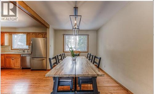 Kitchen and dining area featuring wood-finish flooring, stainless steel appliances, wood cabinetry, and a dark metal linear pendant light fixture - 110 Wren Place Unit# Upper, Kitchener, ON - Indoor Photo Showing Dining Room