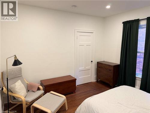 Interior room featuring wood-finish flooring, white walls, and a white paneled door - 207 Charlton Avenue W, Hamilton, ON 