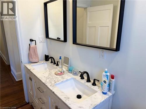 Dual basin vanity featuring a marble-patterned countertop, under-mount sinks, and matte black fixtures - 207 Charlton Avenue W, Hamilton, ON 