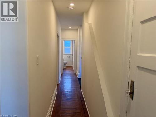 Hallway featuring wood-finish flooring, recessed lighting, and a white interior door with a clear glass knob - 207 Charlton Avenue W, Hamilton, ON 