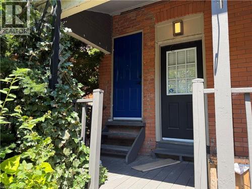 Brick facade featuring two entry doors, one in royal blue and one in black with a window - 207 Charlton Avenue W, Hamilton, ON 