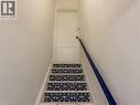 Staircase with contrasting patterned risers and a dark blue handrail - 207 Charlton Avenue W, Hamilton, ON 